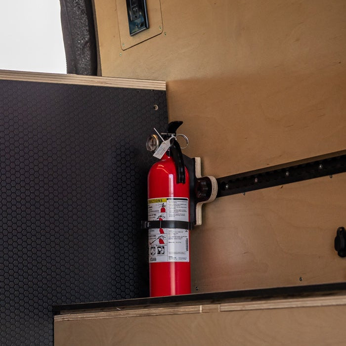 Interior of a van with storage compartments and a fire extinguisher.